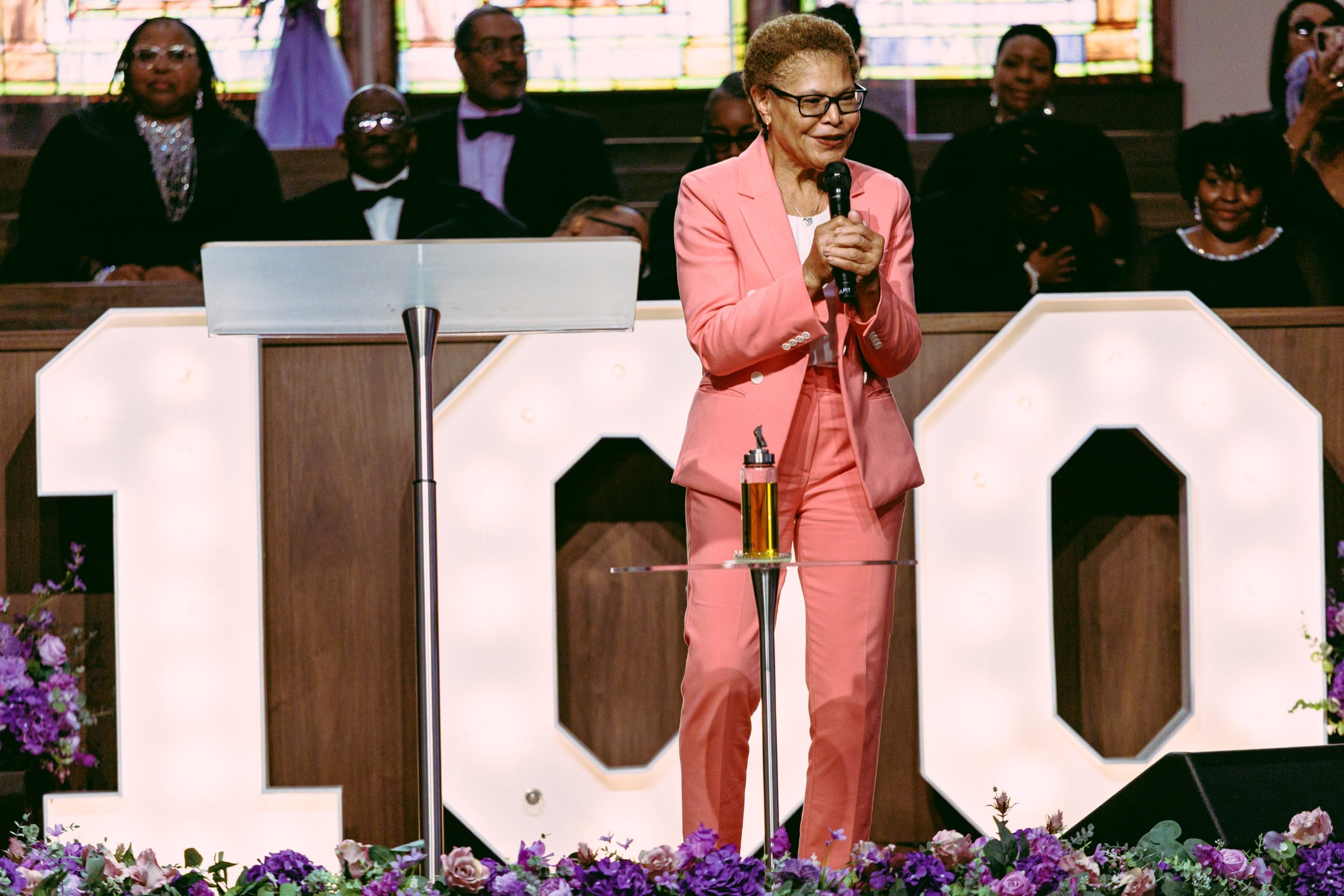 Speaker in a pink suit holding a microphone during a church event