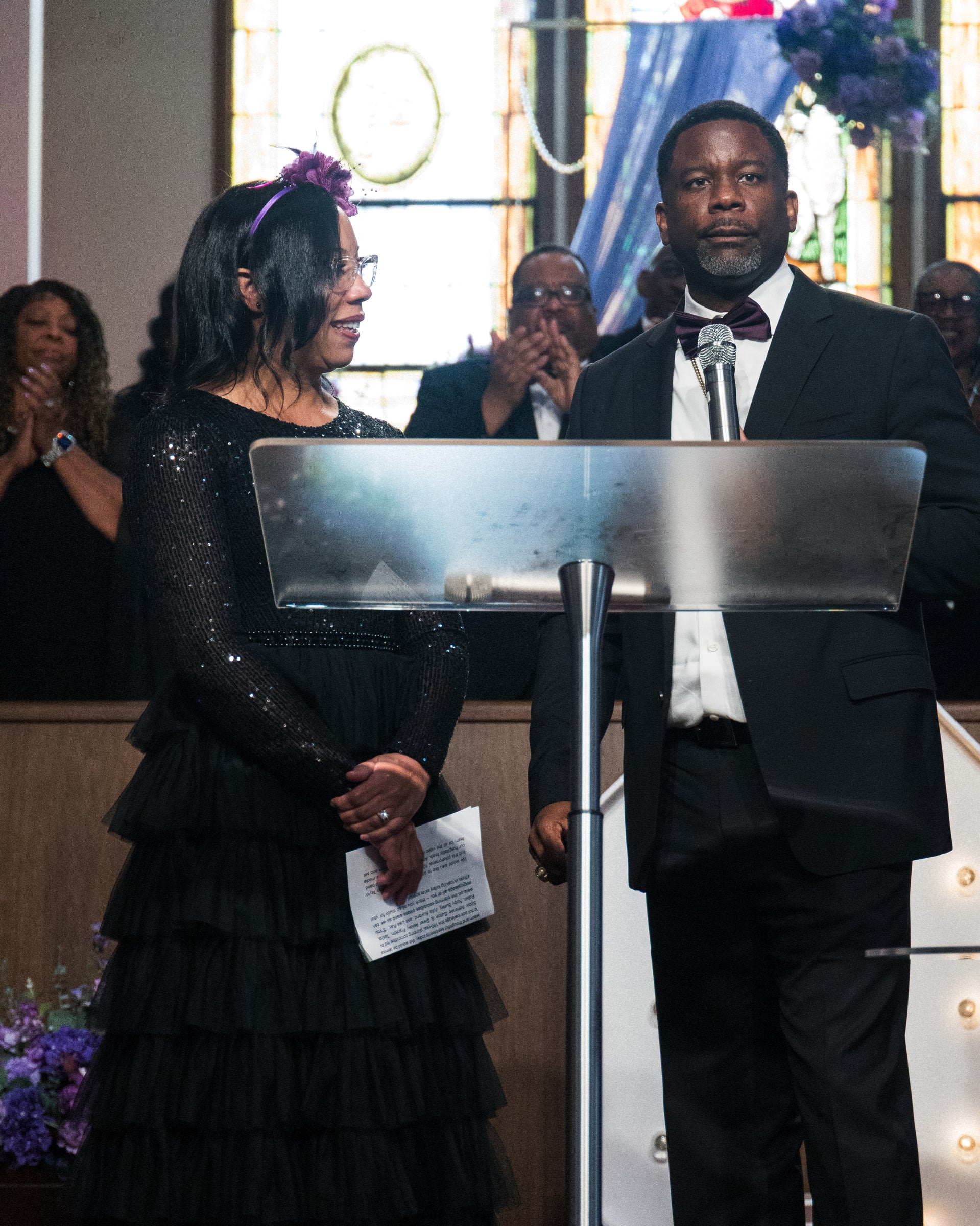 Two people speaking at a clear podium during a formal event